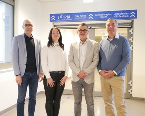 Vier Personen stehen in einem Flur vor einem Schild mit den Aufschriften „Atemtherapiezentrum“ und „Ambulantes OP-Zentrum“.
